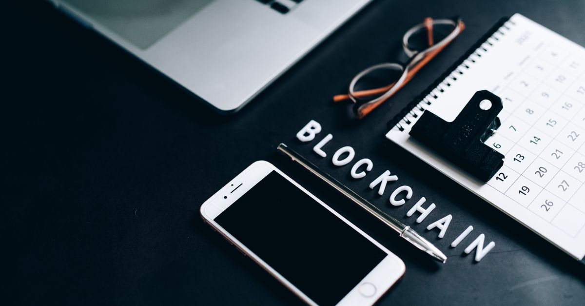 Flat lay of a modern digital workspace with blockchain theme, featuring a smartphone and calendar.